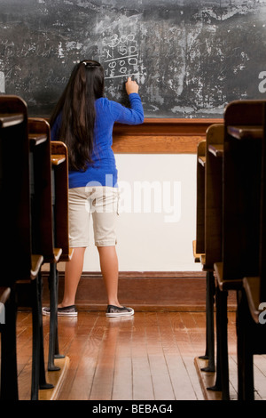 Schoolgirl writing on a blackboard in a classroom Stock Photo
