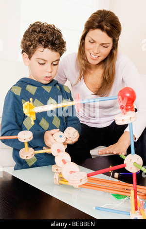 Woman assisting her son in assembling a toy Stock Photo