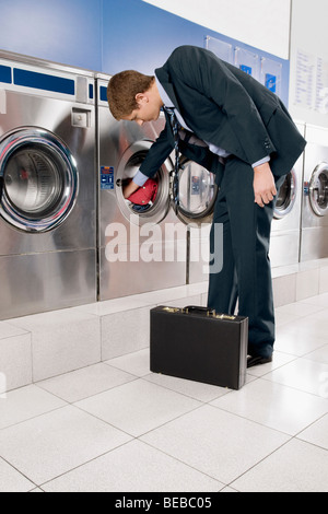 Businessman putting clothes into a washing machine Stock Photo