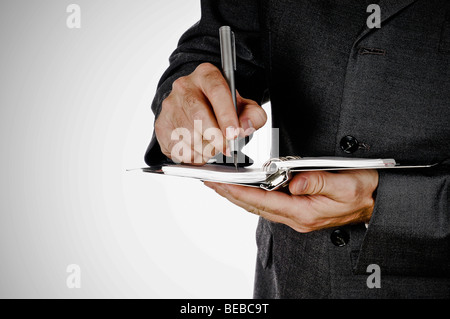 Mid section view of a businessman writing on a spiral notebook Stock Photo