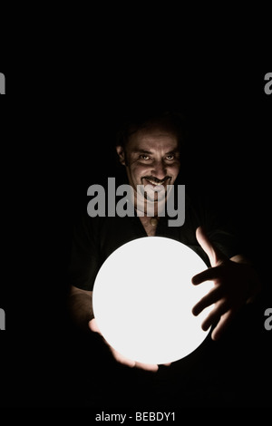 Portrait of a man holding a crystal ball and smiling Stock Photo