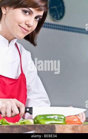 Female chef chopping bell pepper with a knife Stock Photo