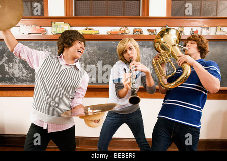 Three students playing musical instruments in a classroom Stock Photo
