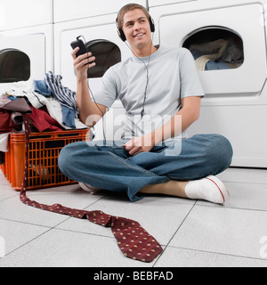 Man listening to an MP3 player in a laundromat Stock Photo