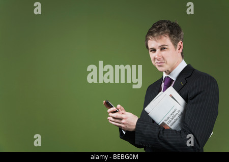 Portrait of a businessman holding a mobile phone and a newspaper Stock Photo