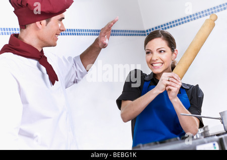 Female and a male chef having a play fight in the kitchen Stock Photo