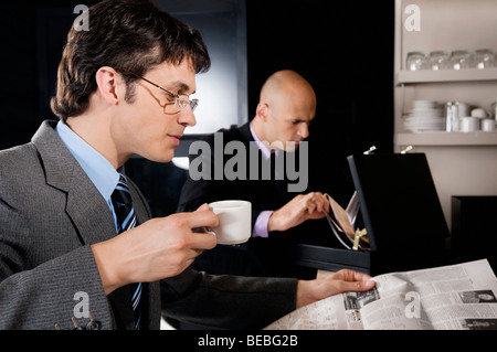 Businessman holding a cup of tea and reading a newspaper Stock Photo