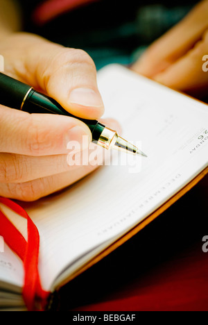 Close-up of a person's hand writing on a diary Stock Photo