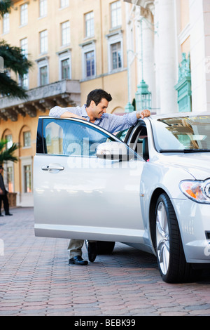 Man leaning against a car door and smiling, Biltmore Hotel, Coral Gables, Florida, USA Stock Photo
