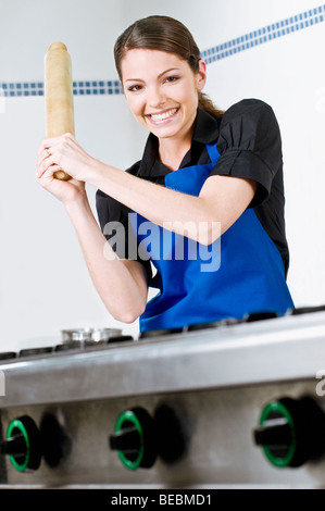 Portrait of a female chef holding a rolling pin and smiling Stock Photo