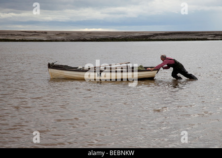 Commercial salmon fisherman pushing a small boat upstream the River Ribble Uk Stock Photo