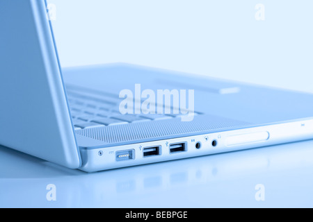 open thin silver laptop computer on white - side view, blue tone Stock Photo