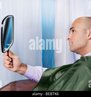 Man looking himself in a mirror after a haircut Stock Photo