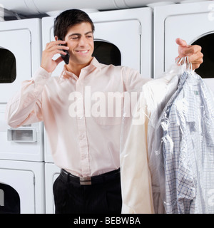 Man talking on a mobile phone in a laundromat Stock Photo