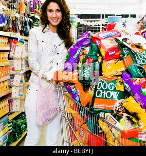 Woman pushing shopping cart loaded with dog foods Stock Photo