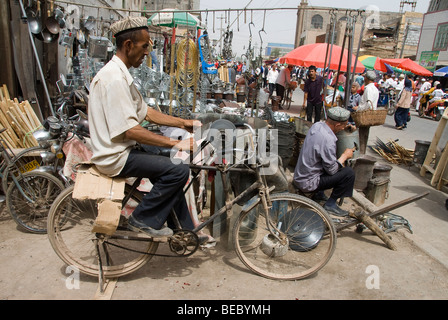 Blacksmith using a bike to sharpen knives in a market of Kashgar, Xinjiang Province, China 2008. Stock Photo