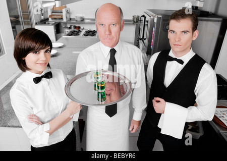 Two waiters and a waitress standing in the kitchen Stock Photo