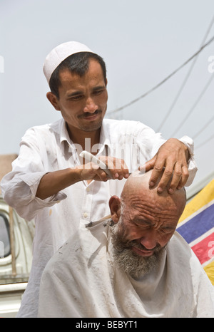 Barber working in a street market of Kashgar, Xinjiang Province, China 2008. Stock Photo