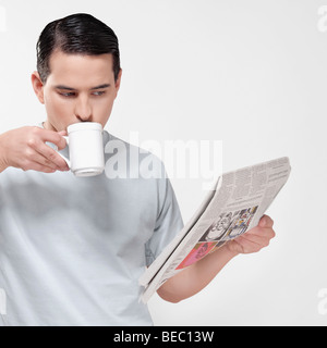 Close-up of a man reading a newspaper and drinking coffee Stock Photo