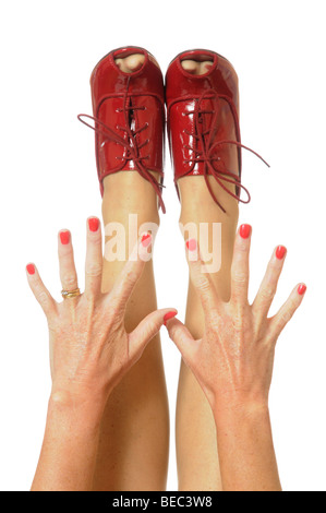 Red painted finger nails with hands outstretched to red high heeled shoes Stock Photo