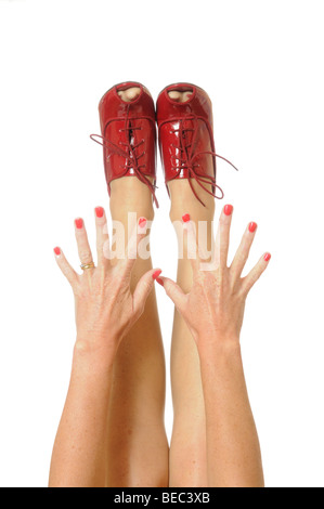 Red painted finger nails with hands outstretched to red high heeled shoes Stock Photo