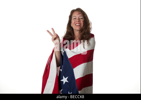 woman wrapped in American flag smiling showing victory sign with fingers Stock Photo