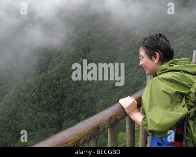 Woman wearing waterproof clothing, on the Mirador Espigon Atravesado viewing point, Laurisilva, El Canal y Los Tilos Biosphere
