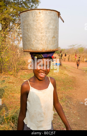 Girl carrying a water jug on her head, African village Sambona, Southern Province, Republic of Zambia, Africa Stock Photo