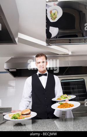 Waiter holding plates of foods and smiling Stock Photo