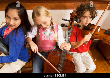 Three students playing musical instruments in a classroom Stock Photo