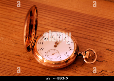 Old open-face watch with flip-top lid on wooden background Stock Photo