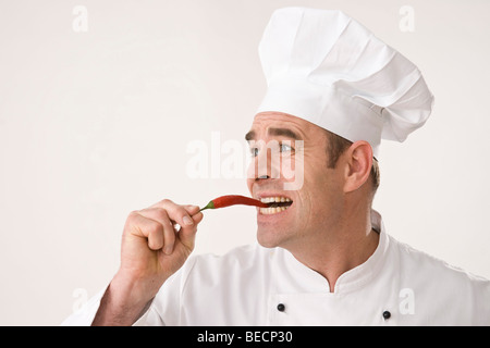 Cook biting into a chili pepper Stock Photo