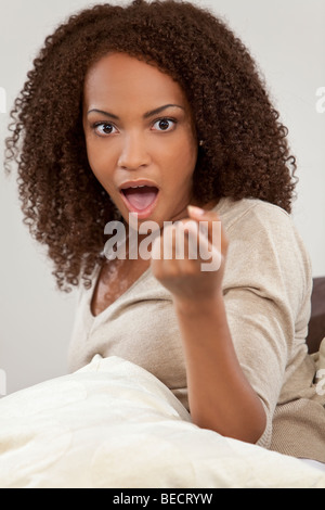 A beautiful mixed race African American girl looking shocked, surprised and pointing at the camera Stock Photo
