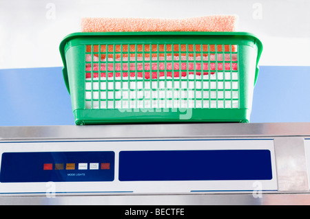 Laundry basket on a washing machine in a laundromat Stock Photo