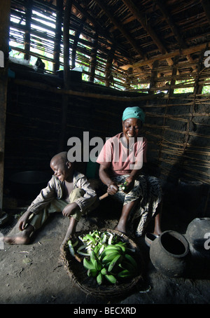 Bakonzo mother and son cooking in mud hut kitchen, Rwenzori Mountains, West Uganda, Africa Stock Photo