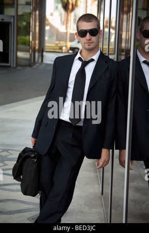 businessman leaning against a modern glass building Stock Photo