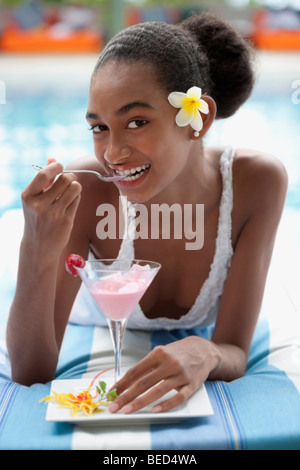Portrait of a woman lying at the poolside and eating ice cream Stock Photo