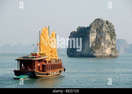 Typical sailing ship, Junk, with two yellow sails, sailing towards a rocky island, Ha Long Bay, Vietnam, Asia Stock Photo