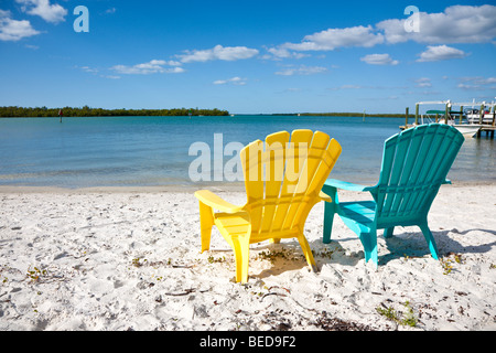 Colorful plastic Adirondak style beach chairs face into the blue ocean in Naples, Florida Stock Photo