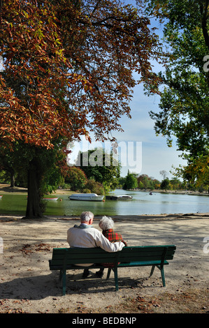 Paris, France - Senior Couple Sitting on Park Bench, From Behind,  Autumn Scenic "bois de vincennes" Garden Pond, sit underneath tree fall scene Stock Photo