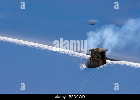 Smoking chimney on a snow-covered roof, Graubuenden, Switzerland, Europe Stock Photo