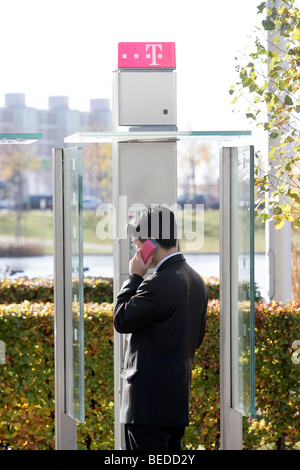 Businessman making a phone call in a public Telekom telephone box, Munich, Bavaria, Germany, Europe Stock Photo