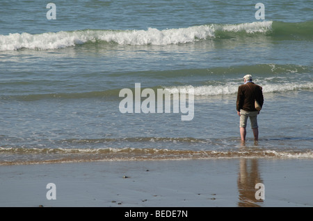 September afternoon - indian summer - a Middle aged man paddling in the waves in the sea in Tywyn Gwynedd north wales UK Stock Photo