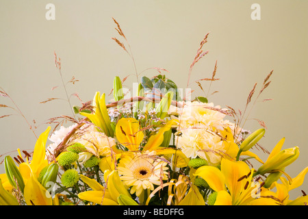 A dispay of joyful summer flowers and grasses of lemon carnations yellow lilies green chrysanthemums and sneezewort Stock Photo