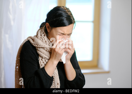 Young woman blowing her nose Stock Photo