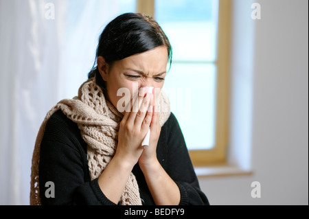 Young woman blowing her nose Stock Photo