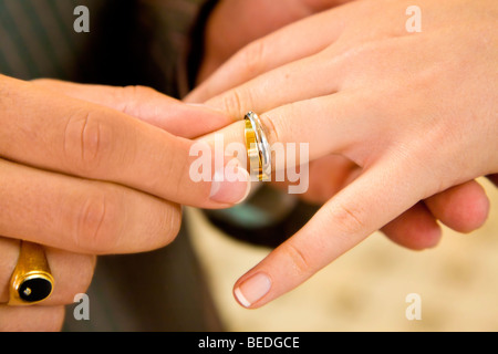 BRIDE AND GROOM EXCHANGING GOLD WEDDING RINGS Stock Photo