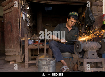 Local Uighur sharpening a knife in a street market of Kashgar, Xinjiang Province, China. Stock Photo