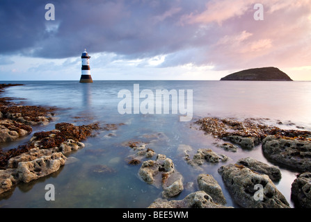 A view of Penmon Lighthouse and Puffin Island at dawn on the coast of Anglesey in North Wales. Stock Photo