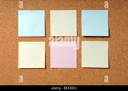 Adhesive note pads of various colors on a cork board Stock Photo
